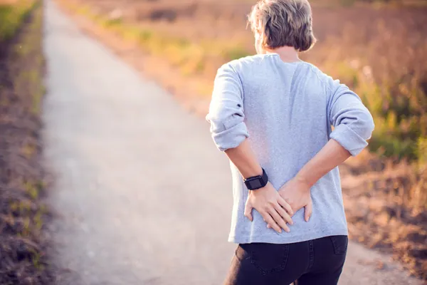 Woman walking outdoors holding her painful hip