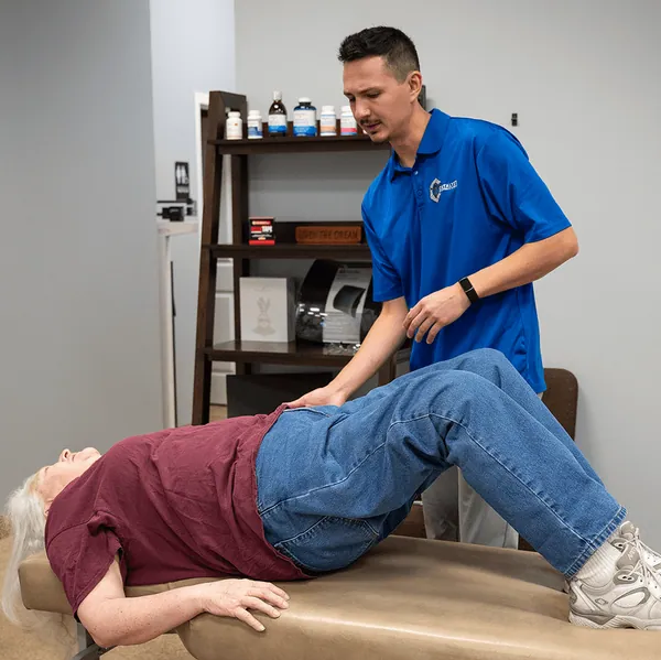 Chiropractor assessing a patient’s low back on the table