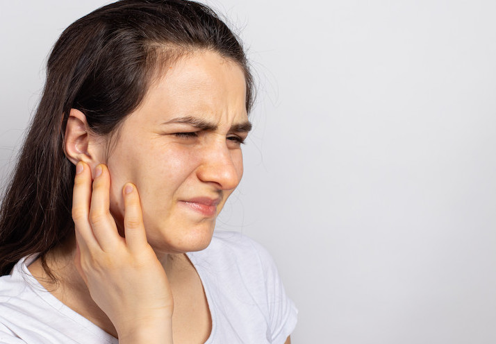 woman holding her jaw due to TMD/TMJ pain